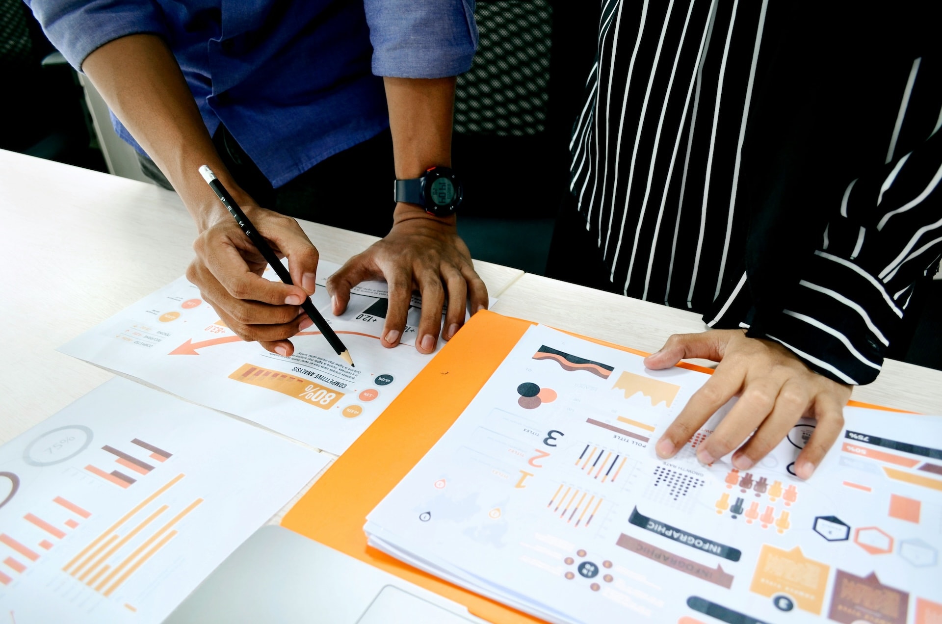 Zwei Personen analysieren gemeinsam Geschäftsdokumente mit Diagrammen am Tisch